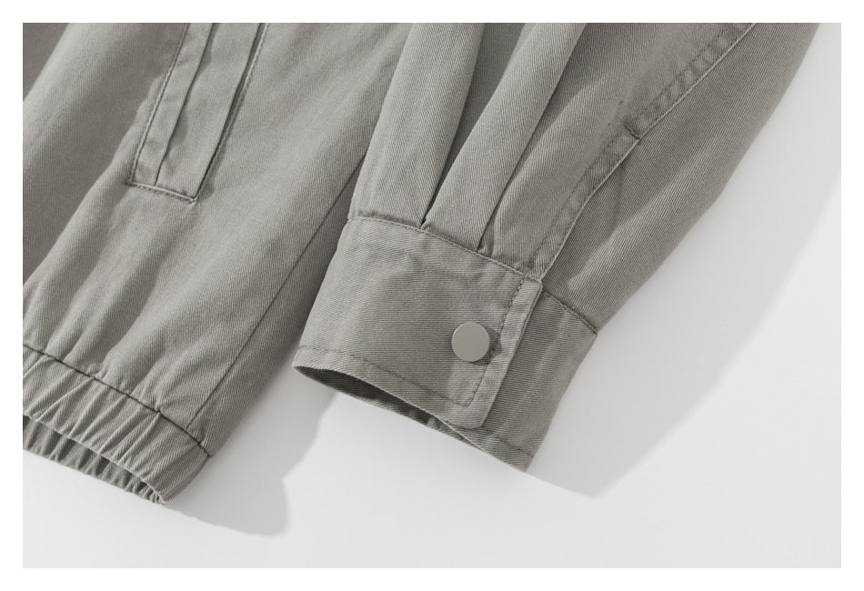 Close-up of the gray jacket's snap-button cuff and gathered hem.
