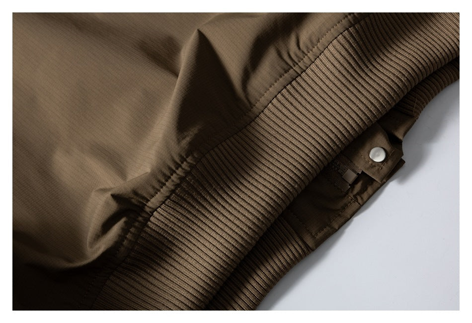 Close-up of the brown jacket's ribbed edge, stitching and snap-fastened tab.