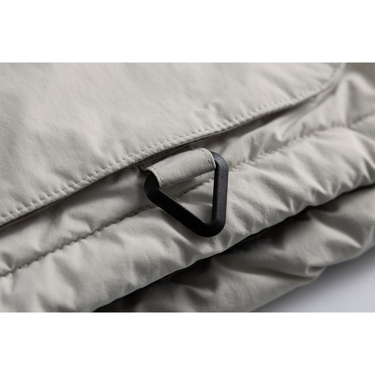Close-up of a black triangular loop attached to a light gray jacket.