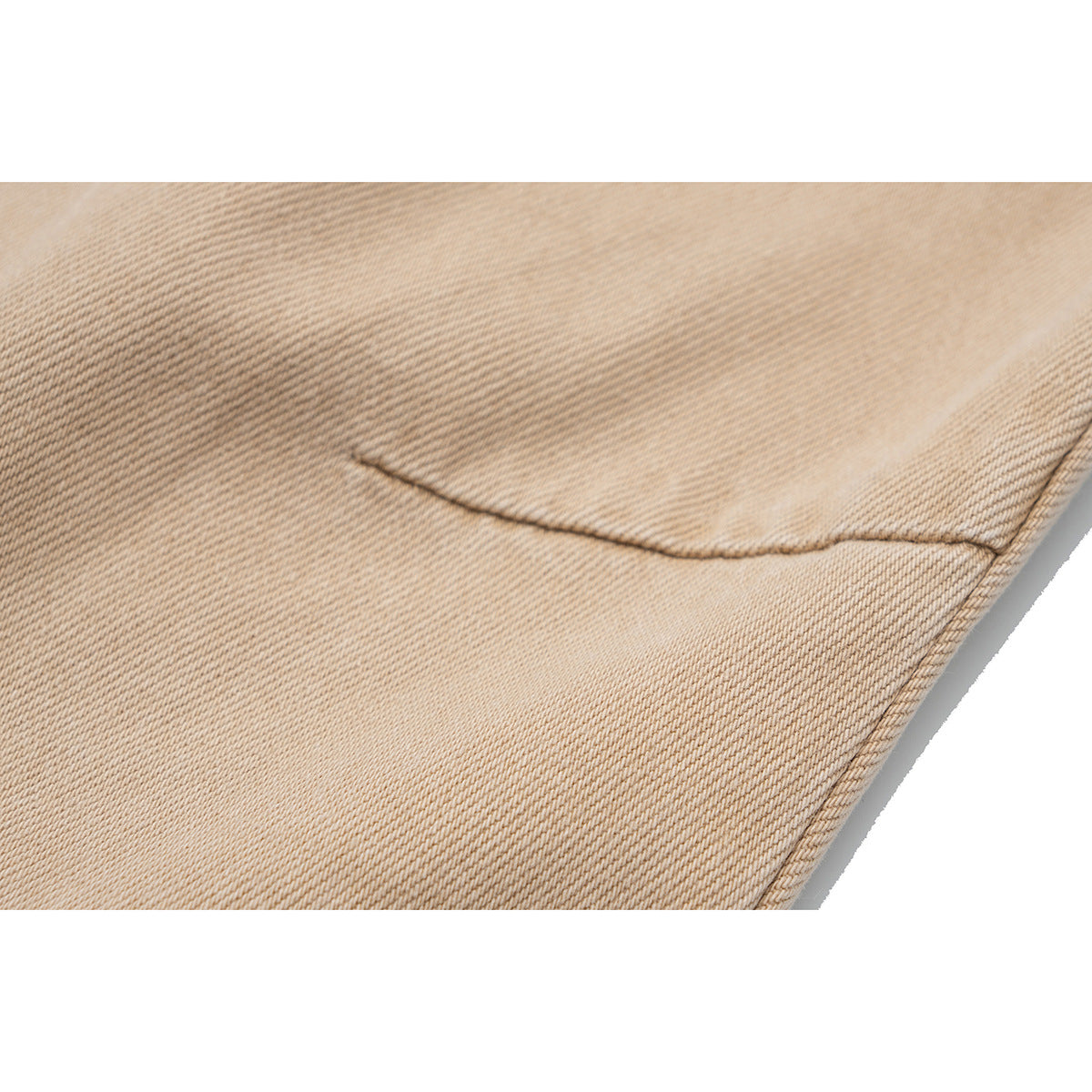 Close-up of beige pants showing the diagonal fabric weave and a stitched seam.