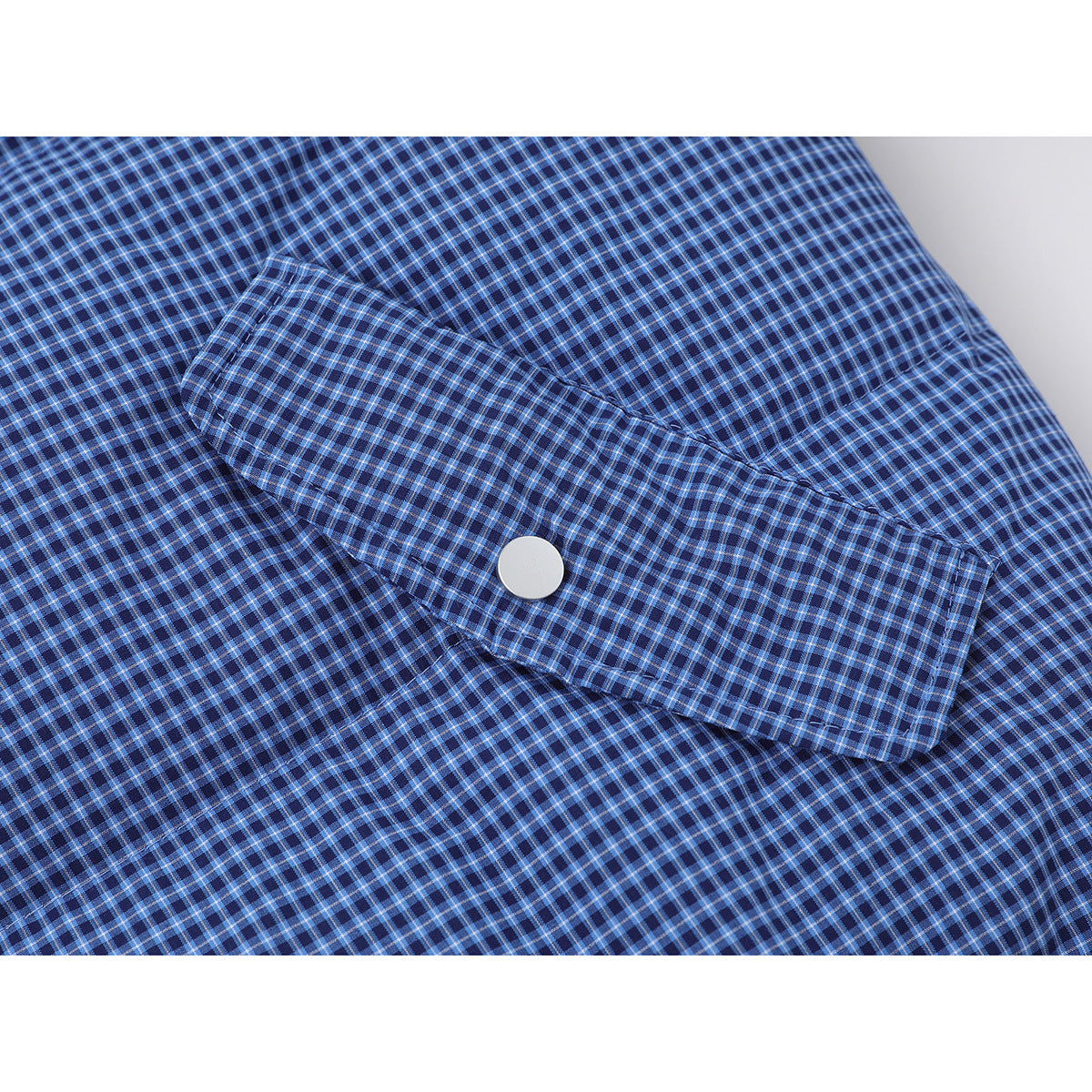 Close-up of a blue checked jacket's snapped sleeve tab against the jacket body.