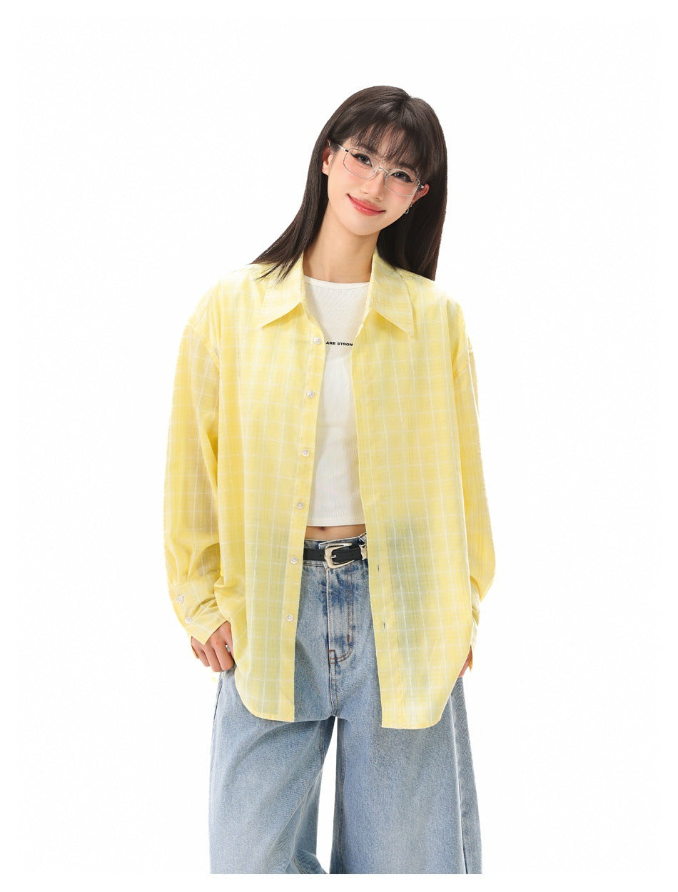Model in yellow plaid button-up shirt worn open over a white top and light blue jeans, close-up