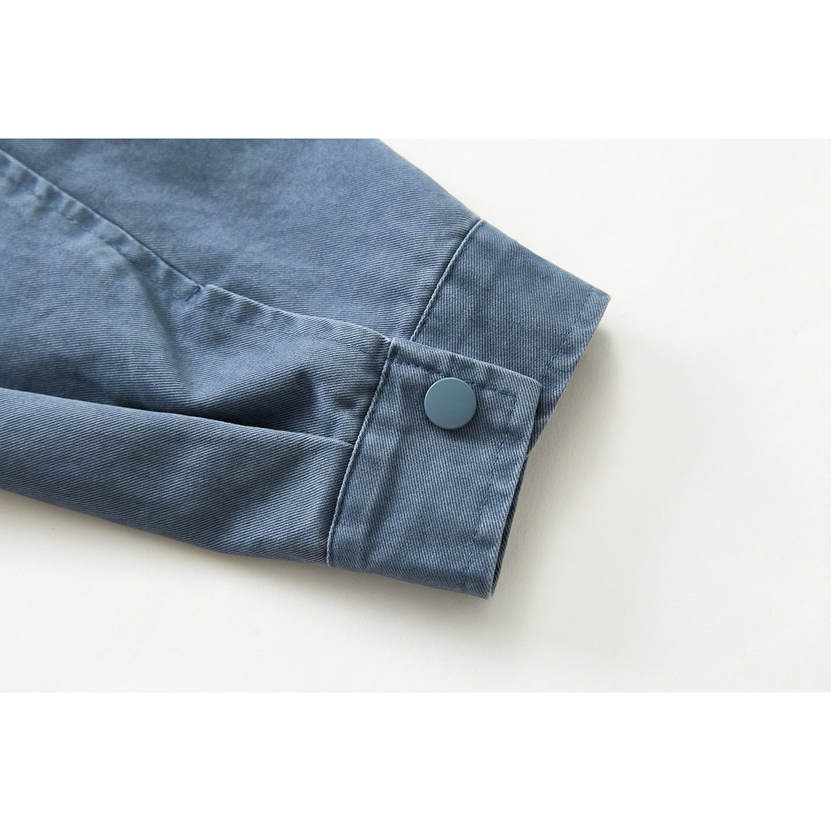 Close-up of the blue jacket sleeve cuff with a matching snap button.