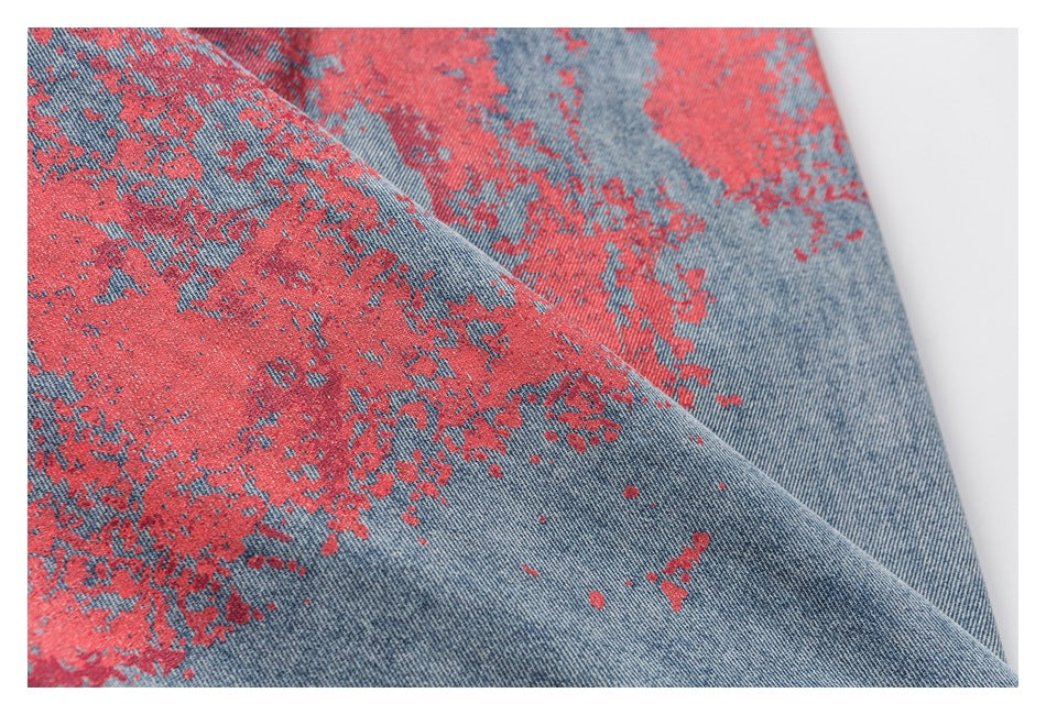 Close-up of distressed red pattern across blue denim fabric.