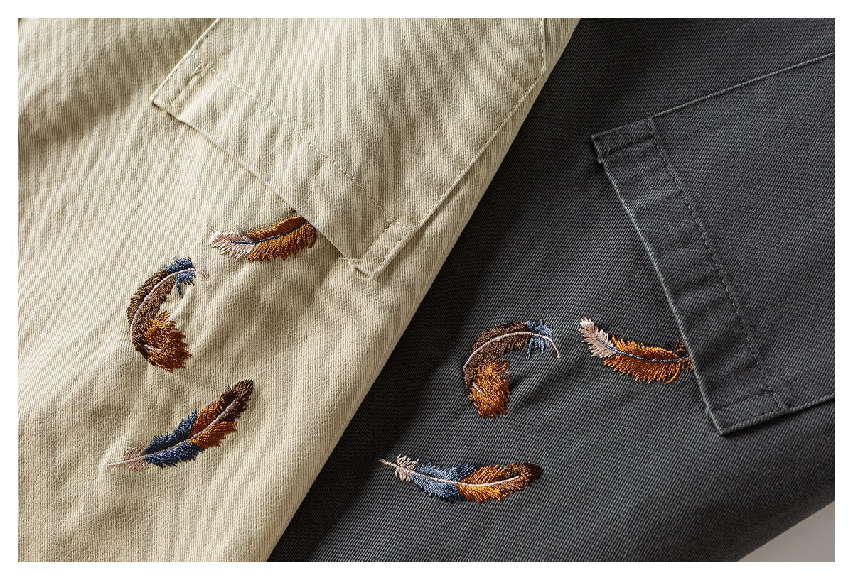 Beige and charcoal versions of a twill jacket, each with a chest pocket and multicolored feather embroidery.
