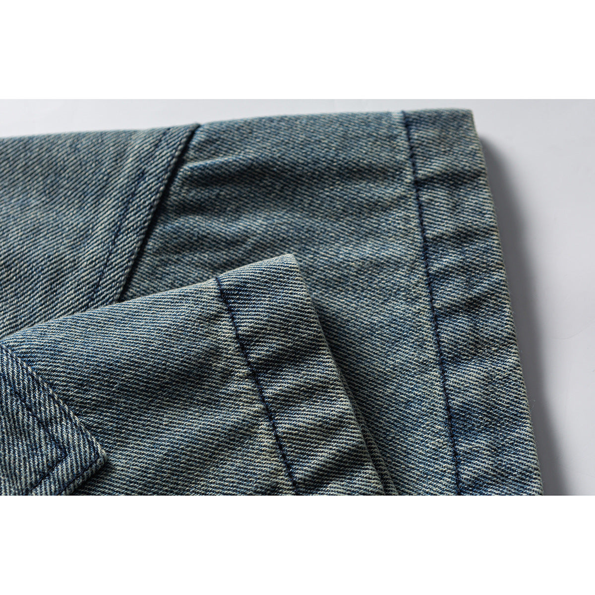 Close-up of blue denim shorts showing folded fabric, a hem edge, and stitching.