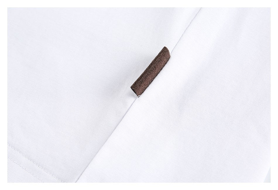 Close-up of a small plain brown fabric tab on white fabric.