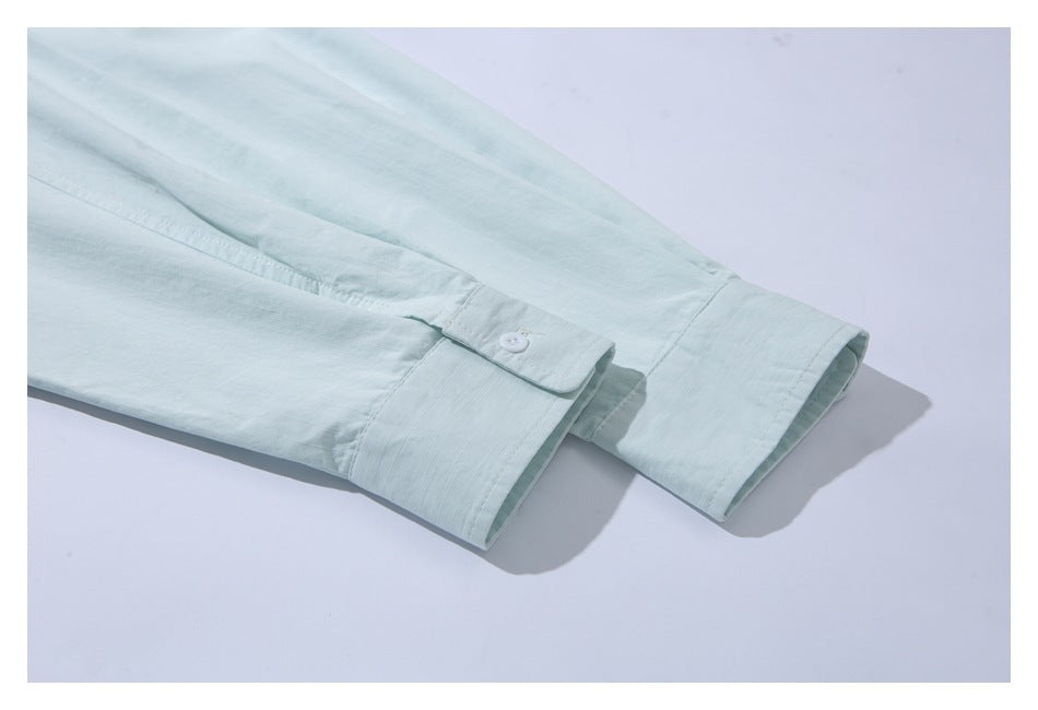 Close-up of pale mint shirt sleeves with buttoned cuffs.