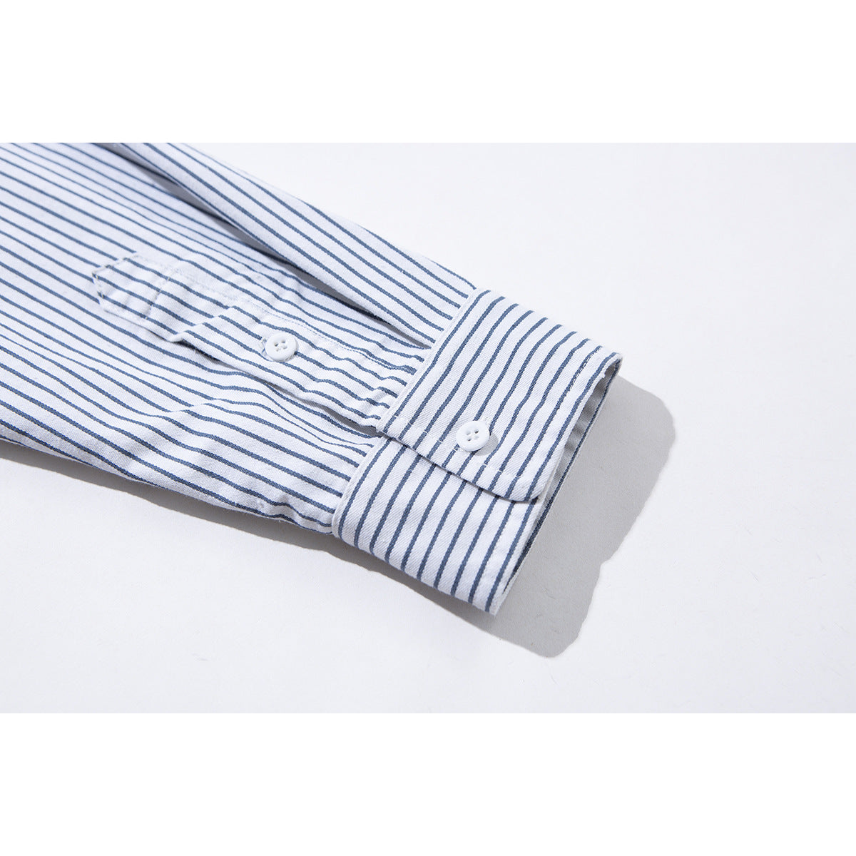 Close-up of a white shirt sleeve with thin blue stripes, showing the buttoned cuff and sleeve placket.