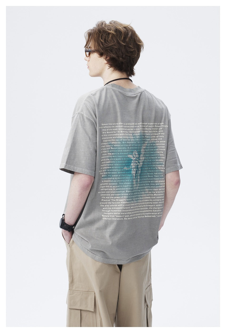 Rear view of a model wearing a light gray oversized T-shirt with a large block of English text on the back.
