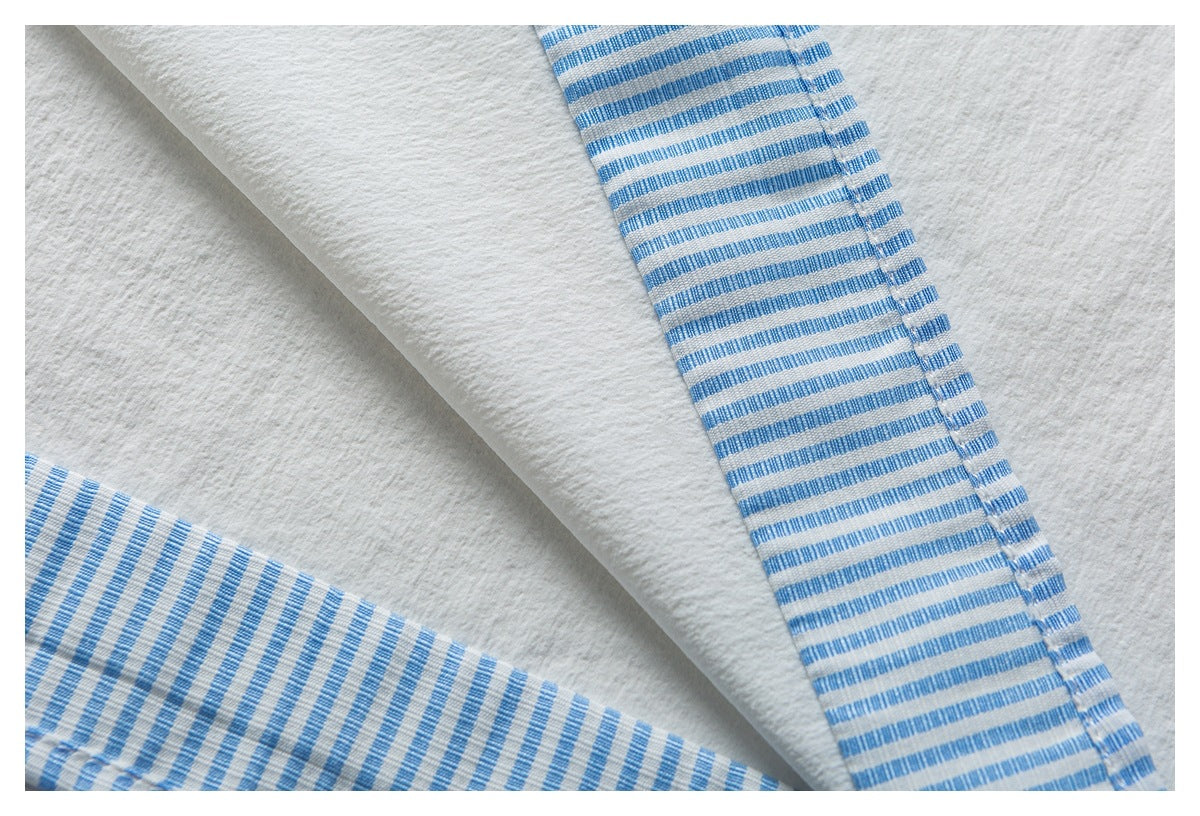 Close-up of white fabric edged with blue-and-white striped binding.