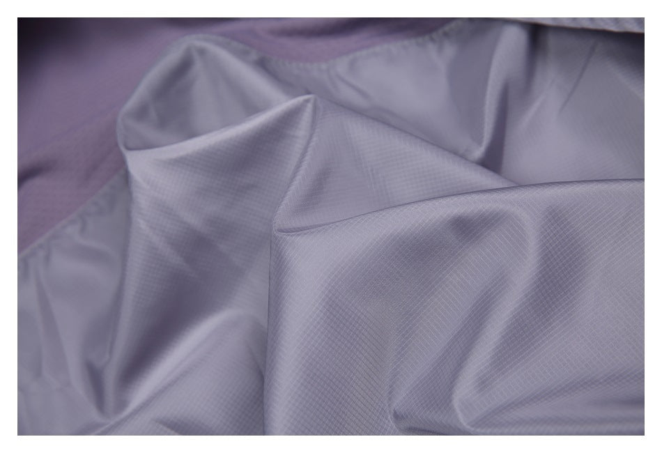 Close-up of light lavender fabric with a fine grid texture and a glimpse of purple mesh lining.