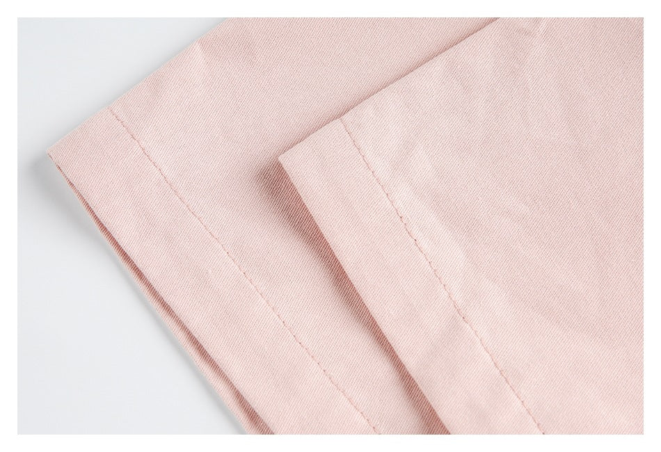 Close-up of pale pink fabric with a stitched folded hem.