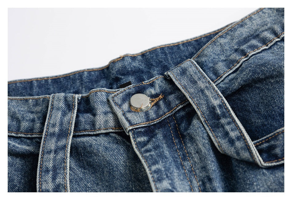Close-up of the blue denim jeans' metal waistband button, belt loop and fly stitching.