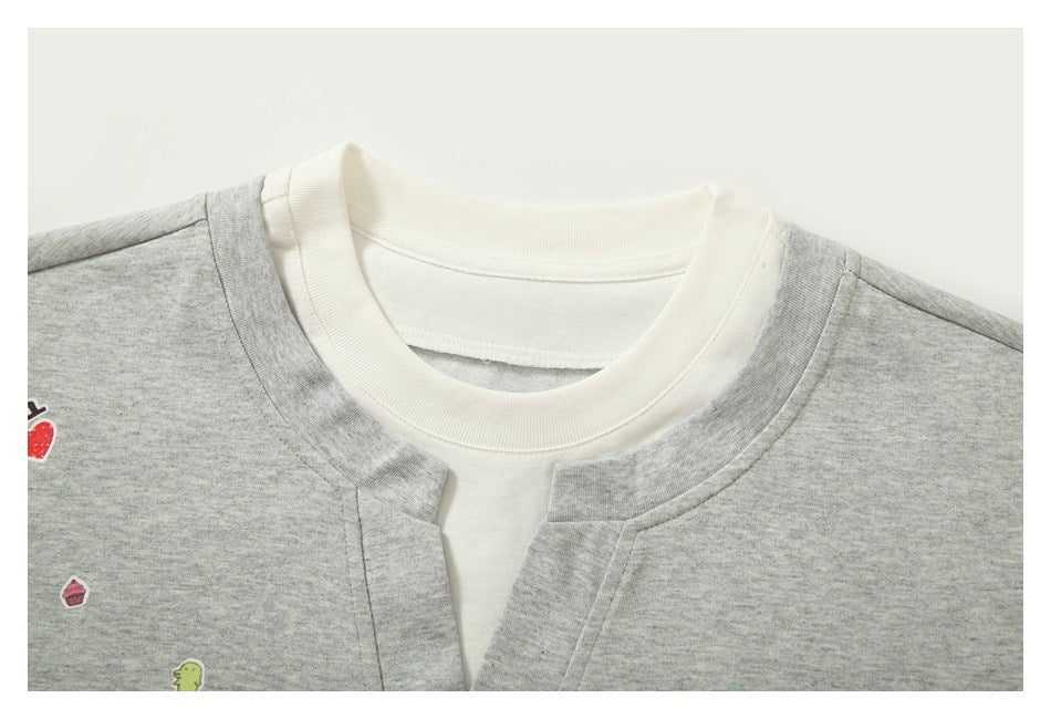 Close-up of a heather-gray shirt with a white ribbed crew neckline and small colorful printed motifs.