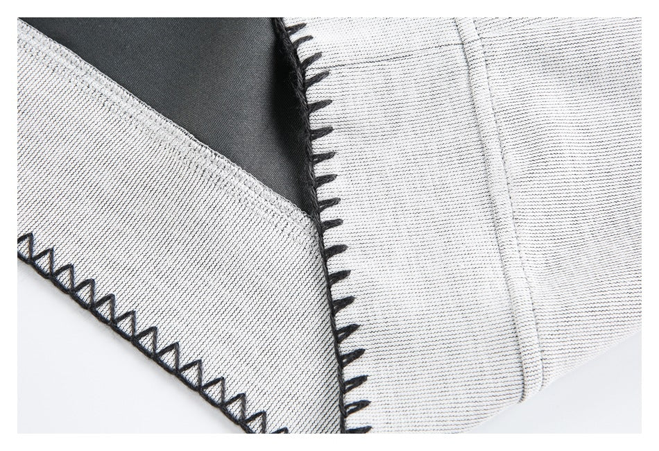 Close-up of light gray garment panels meeting at a seam, with black blanket stitching along the edges.