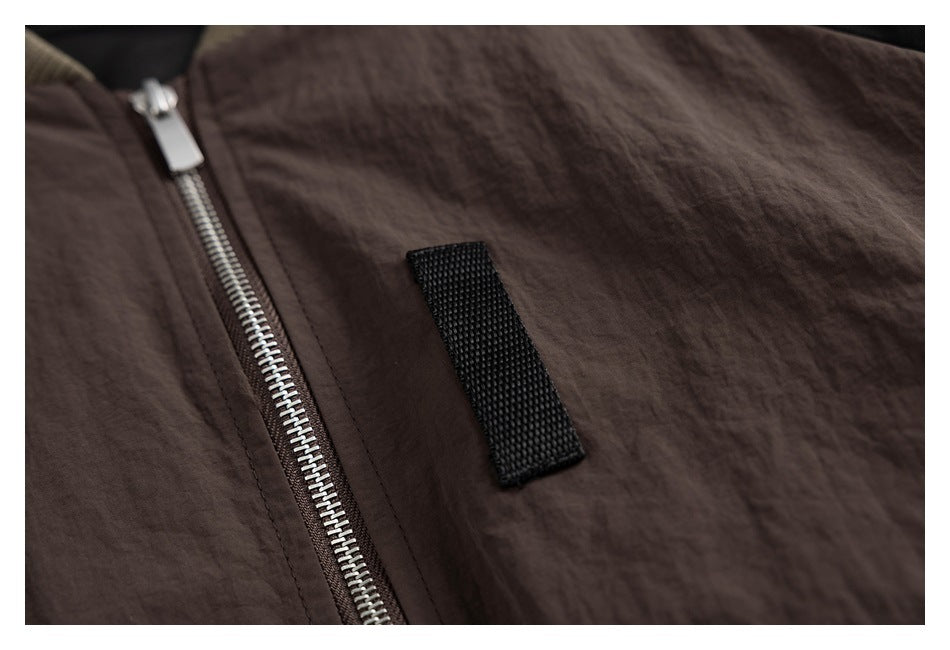 Close-up of a dark brown jacket front with a silver zipper and a black fabric tab.