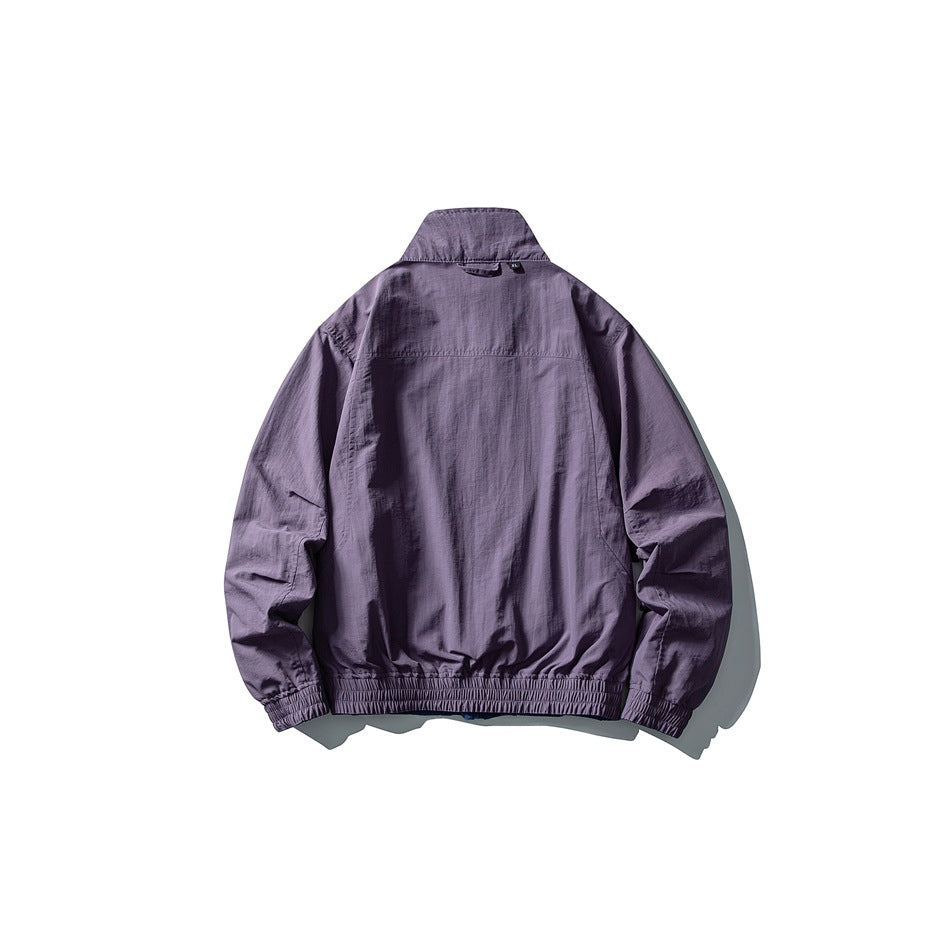 Back view of a muted purple jacket with a stand collar, a horizontal shoulder seam, and elasticated cuffs and hem.