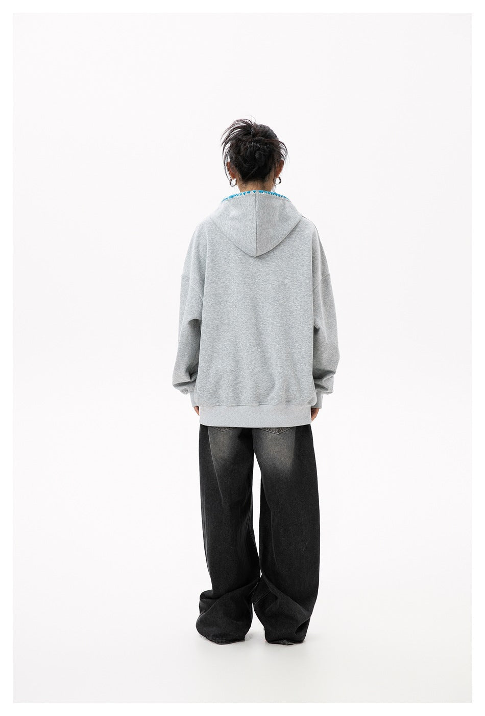 Back view of a model wearing a heather gray hoodie with hood down and wide-leg black jeans