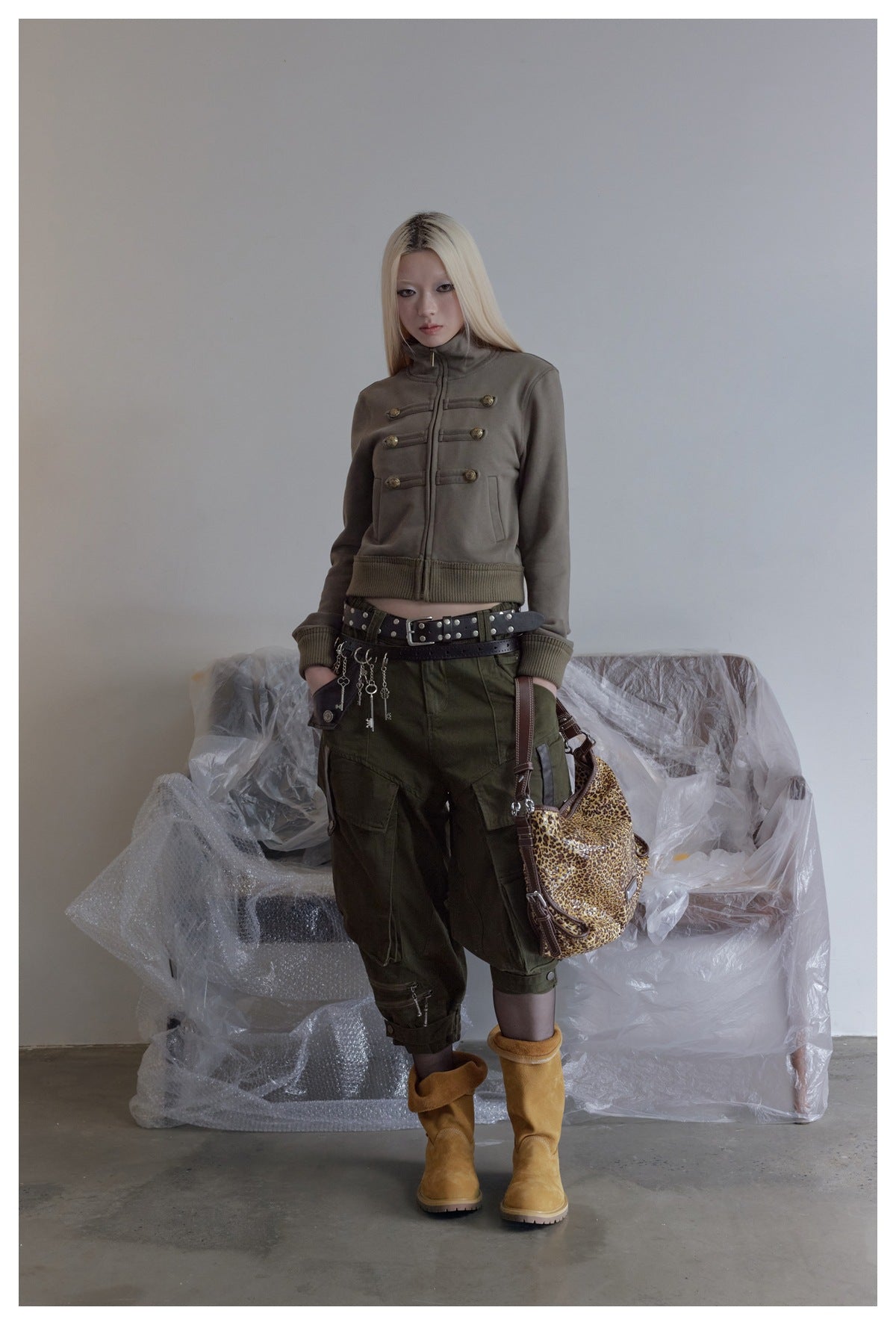 Model wearing the grey-green cropped zip jacket with olive cargo pants, yellow boots and a leopard-print bag
