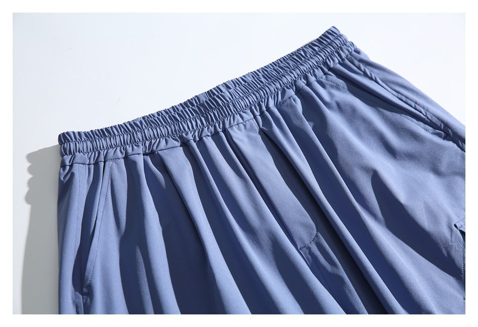 Close-up of the gathered elastic waistband and upper pocket area of slate blue pants.