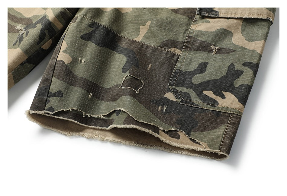 Close-up of a camouflage cargo short leg showing a flap pocket and a raw, frayed hem.