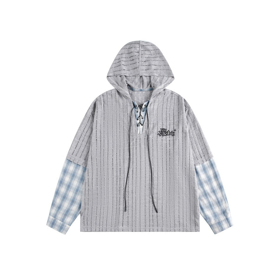 Gray striped distressed knit hooded top with lace-up neckline, blue plaid sleeves and black chest embroidery, flat lay