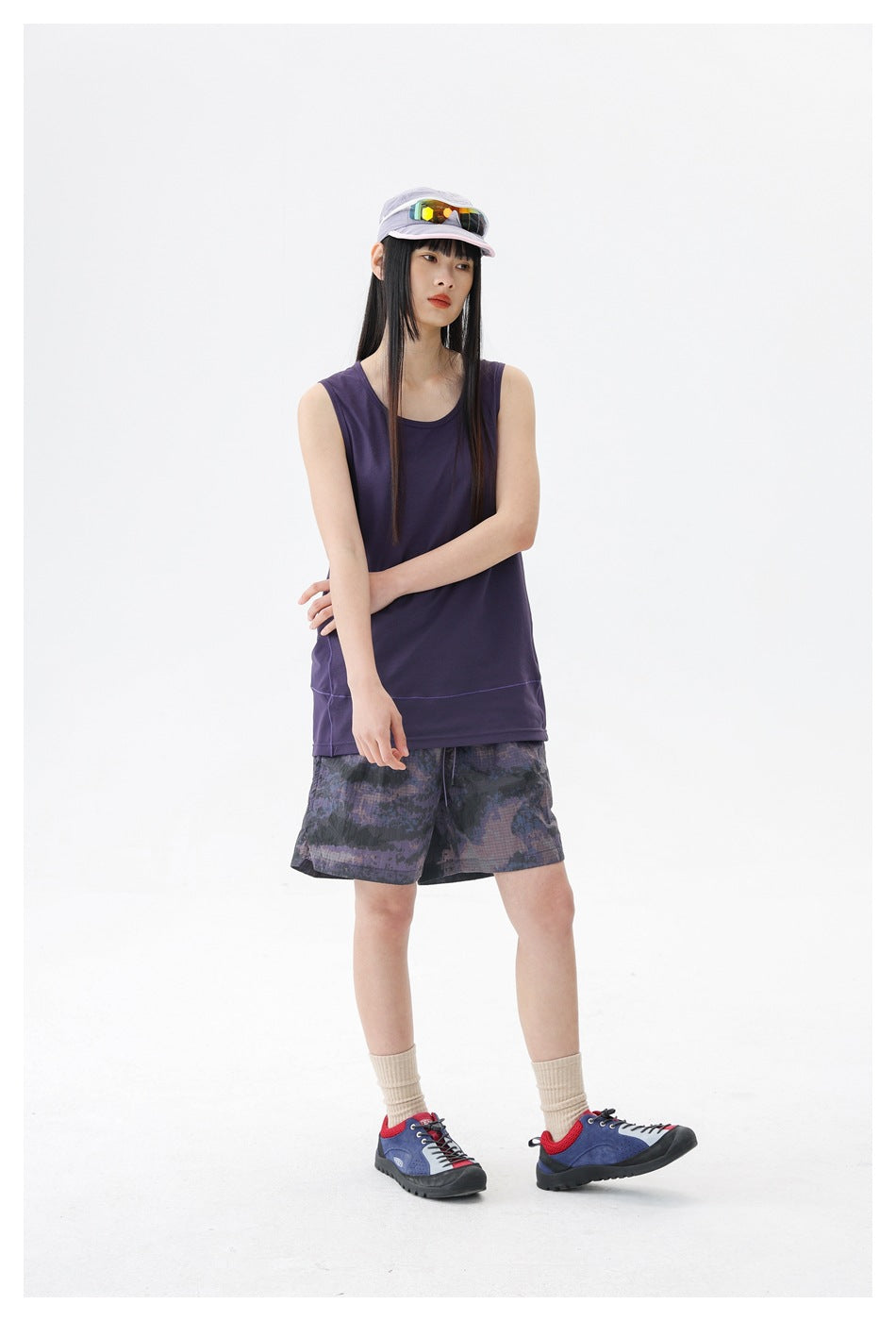 Model wearing a dark purple sleeveless top and purple-gray patterned shorts, shown at a slight angle.
