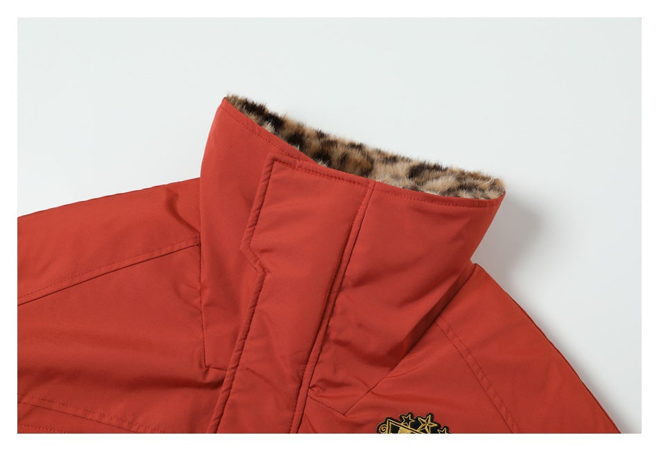 Close-up of a rust-red coat collar with brown faux-fur lining and part of an embroidered crest.