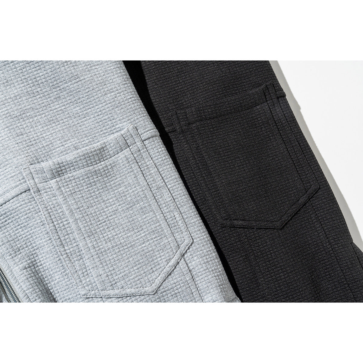 Close-up of large angular pockets on light gray and black textured zip jackets.