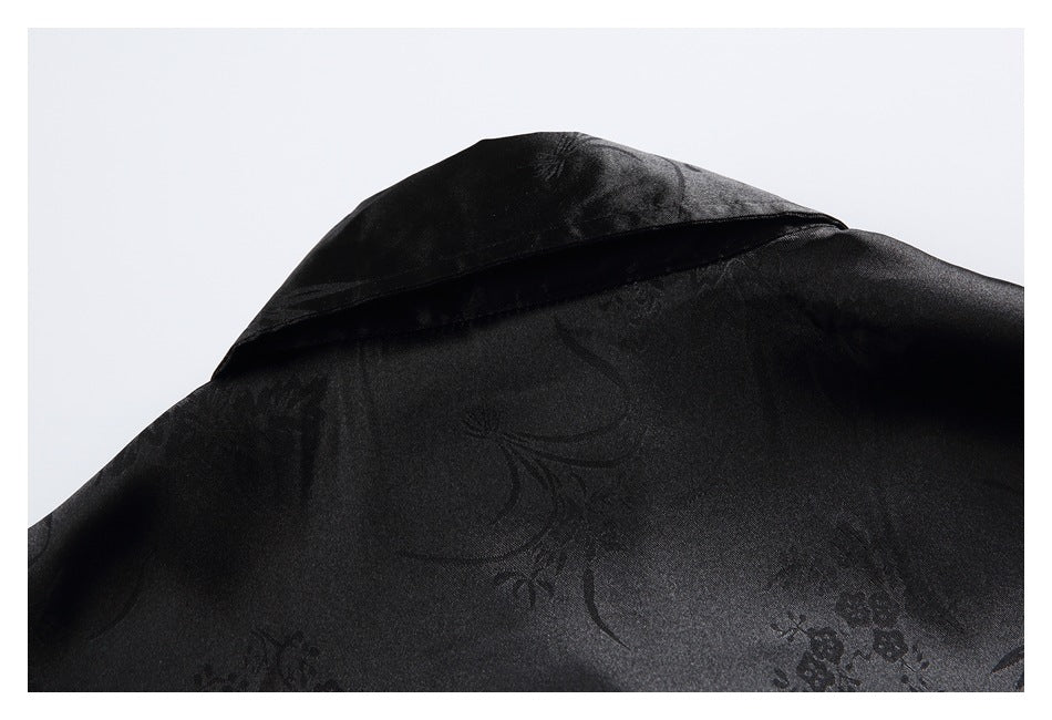 Close-up of black floral-patterned fabric with a folded edge and subtle sheen.