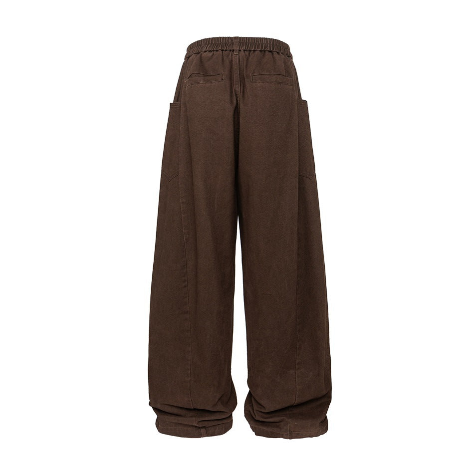 Back view of loose, wide-leg brown trousers with an elastic waist, two rear pockets, and side pockets.