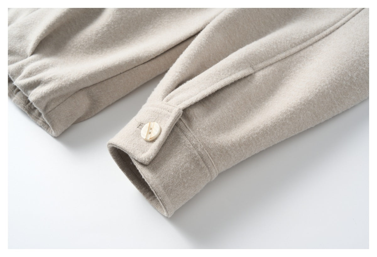 Close-up of a light beige sleeve cuff with a pale button and stitched seam.