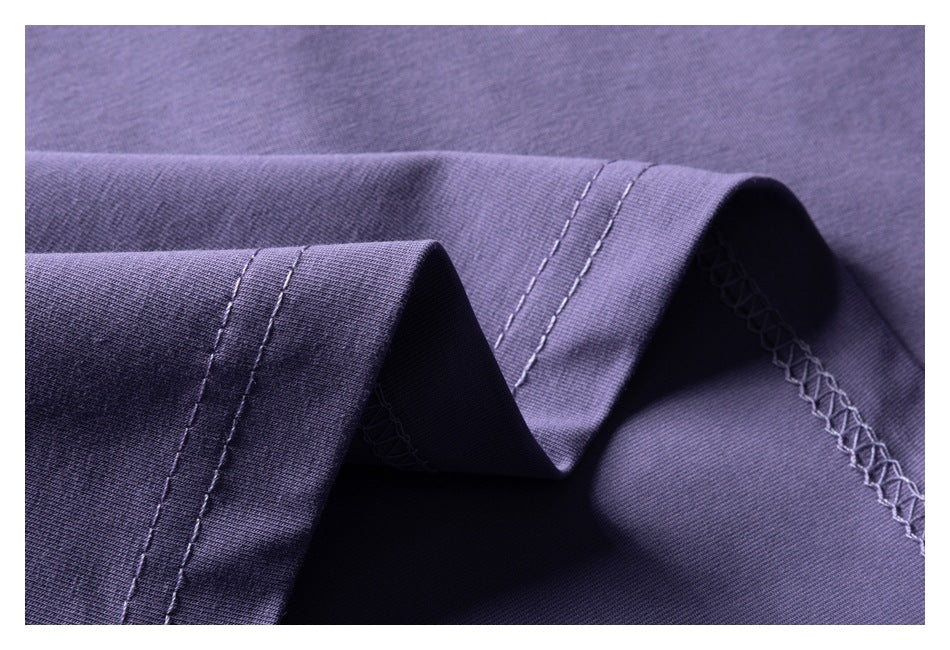 Close-up of lavender-purple garment fabric showing folded seams and overlock stitching.