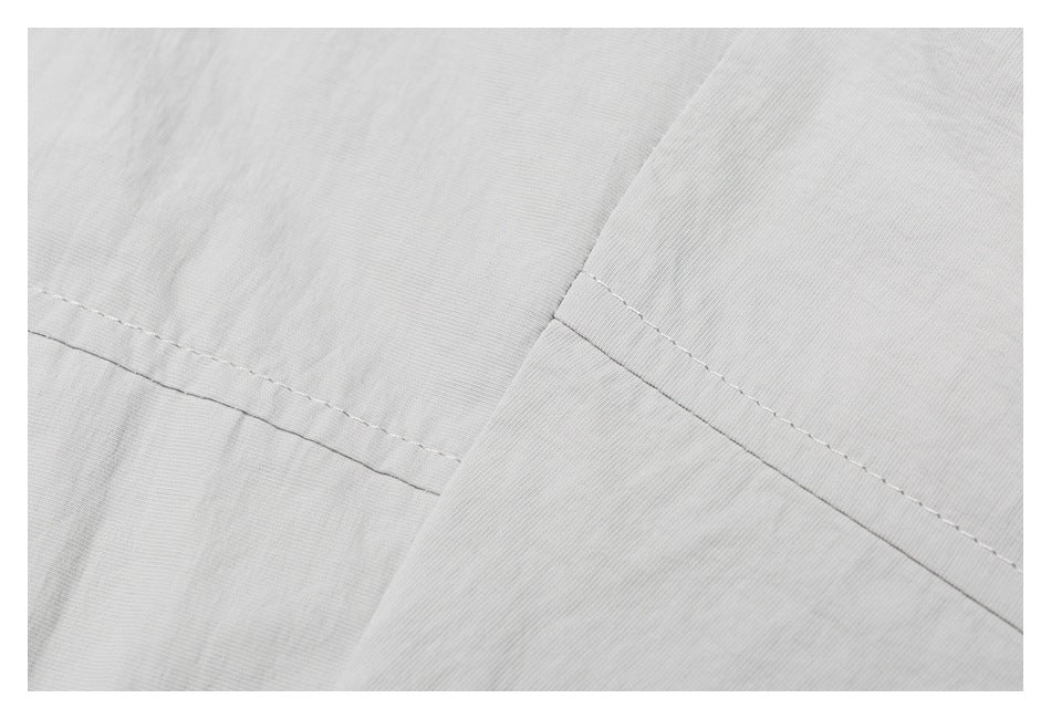 Close-up of light gray garment panels joined by a diagonal seam with visible stitching.
