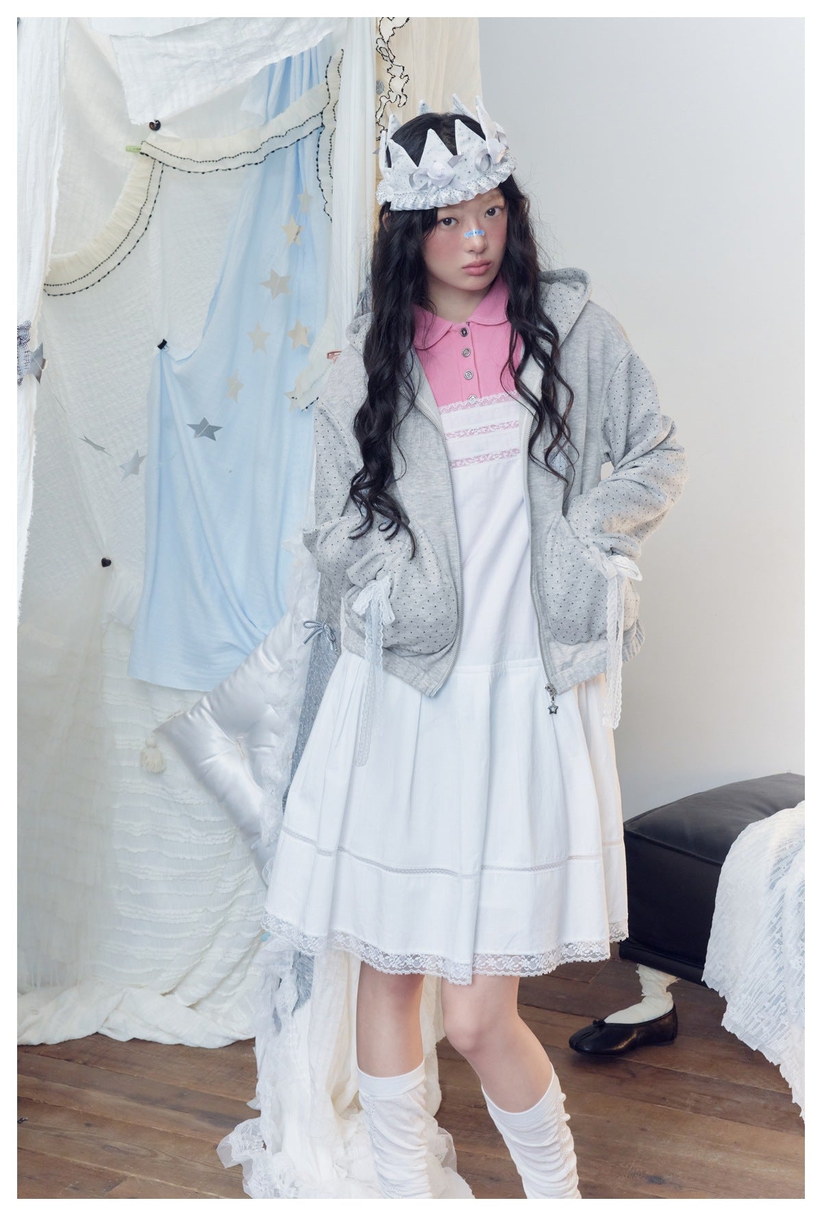 Model wearing a light gray dotted zip hoodie over a white lace-trim dress with a pink collar.