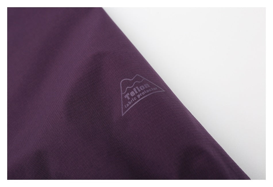 Close-up of a small mountain-shaped English logo printed on purple fabric.