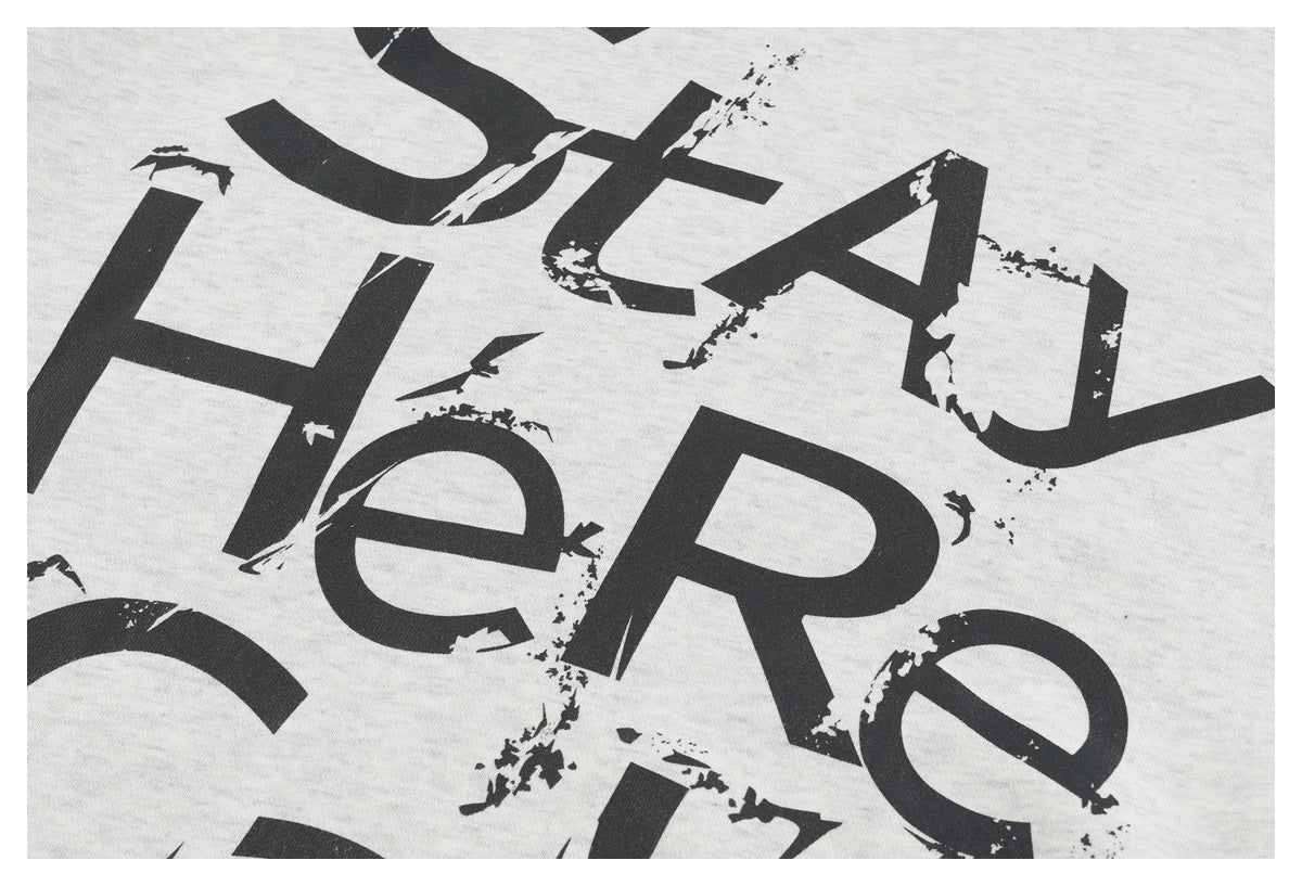 Close-up of distressed black lettering printed on light gray fabric.