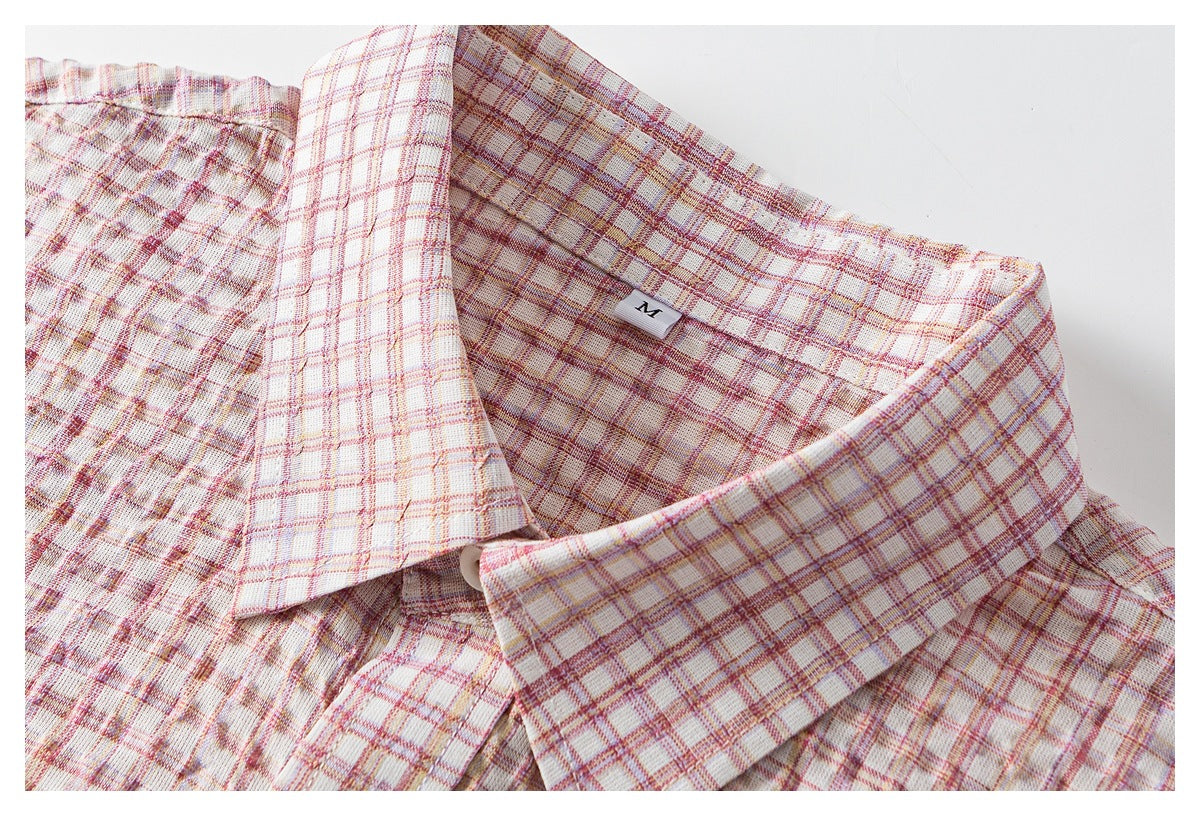 Close-up of the pointed collar and neckline of a cream shirt with pink and muted gold plaid.