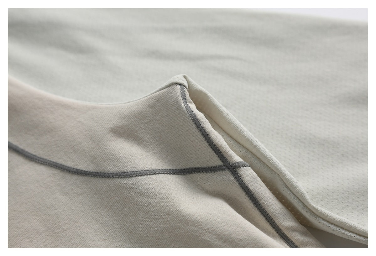 Close-up of light beige garment fabric and gray overlock stitching along a seam.