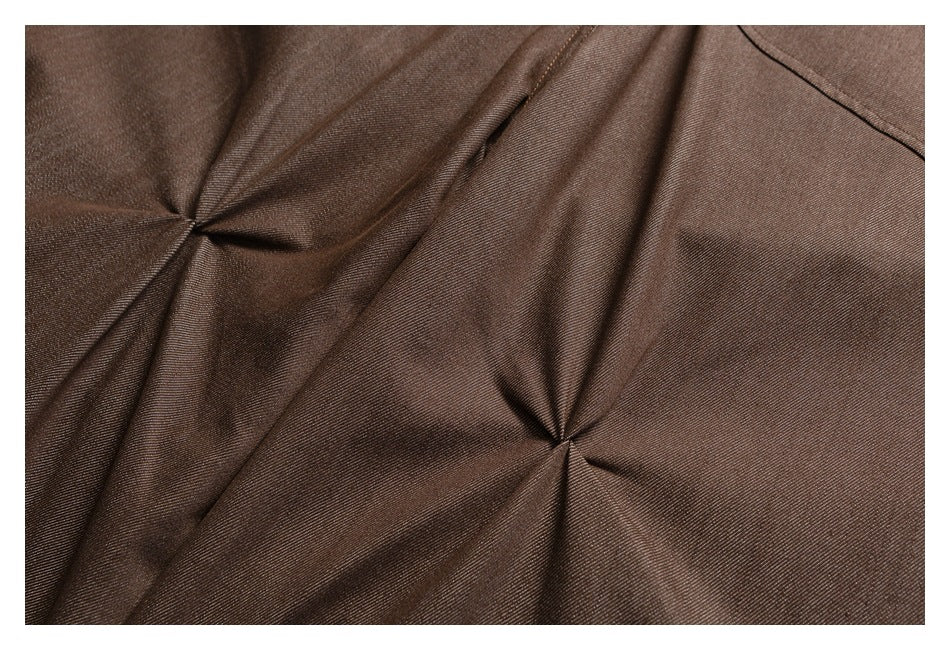 Close-up of dark brown trouser fabric gathered into stitched folds.