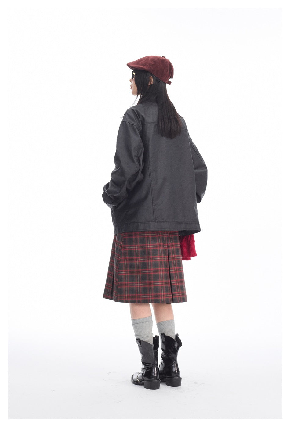 Rear view of a model wearing an oversized black jacket with a red-and-black plaid skirt.