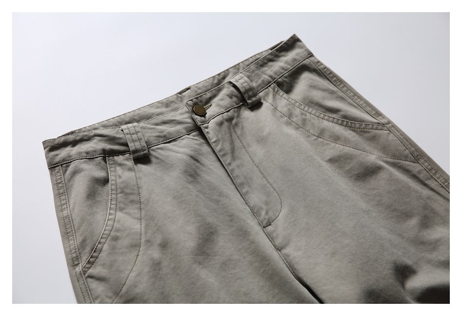Close-up of the gray pants' front waistband, button, belt loops, fly, and curved pockets.