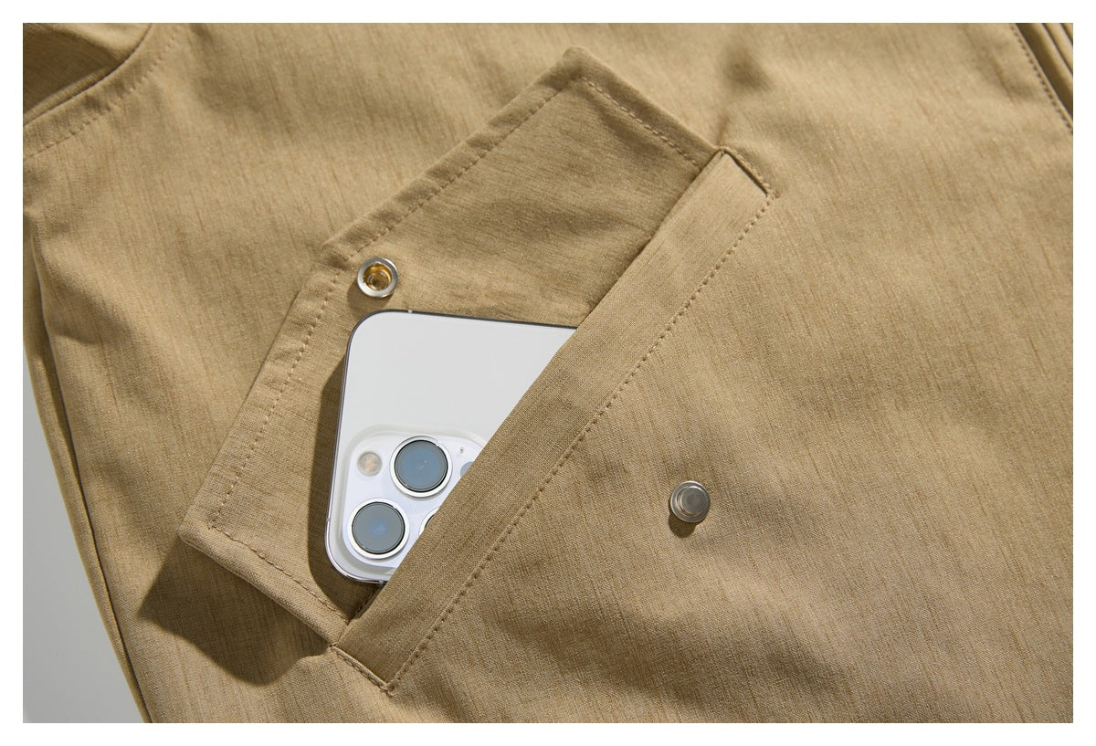 Close-up of a snap-button flap pocket on a tan jacket, with a phone tucked inside.