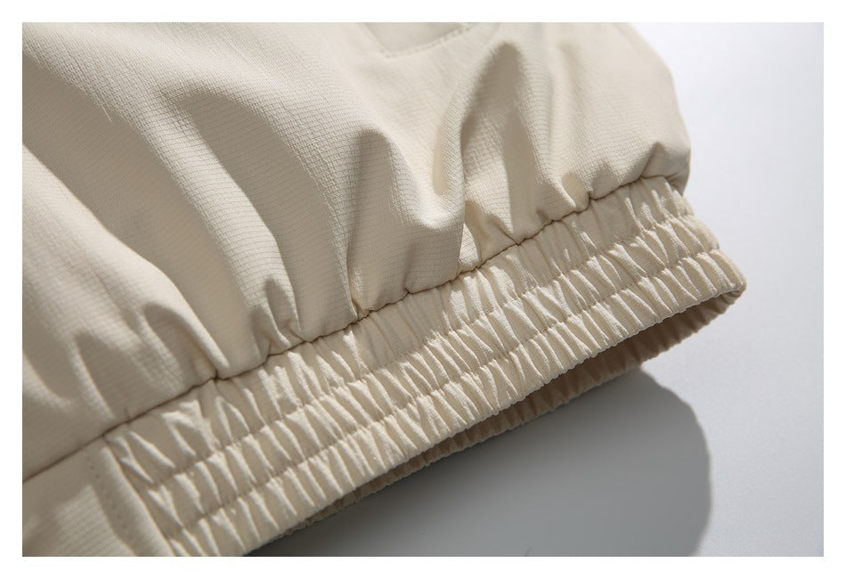 Close-up of a beige jacket's gathered elastic hem and textured shell.