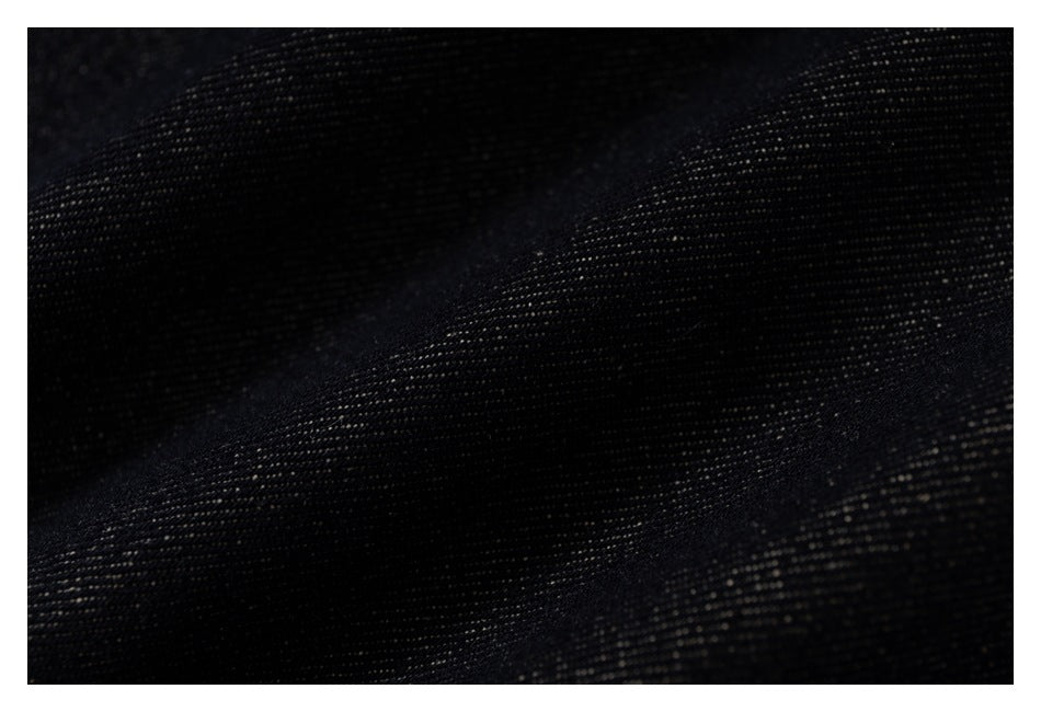 Macro view of dark denim fabric showing its woven texture and folds.