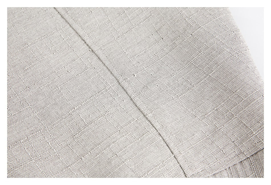Close-up of light beige textured garment fabric showing a seam and stitched panel lines.
