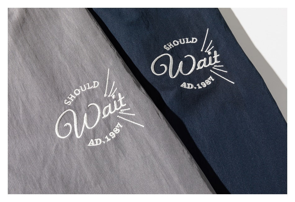 Gray and navy jacket fabric panels with matching white embroidered lettering and rays.