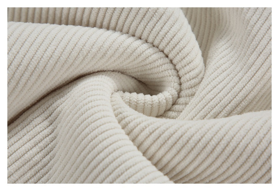 Close-up showing the cream jacket's fine vertical corduroy ribs and folds.