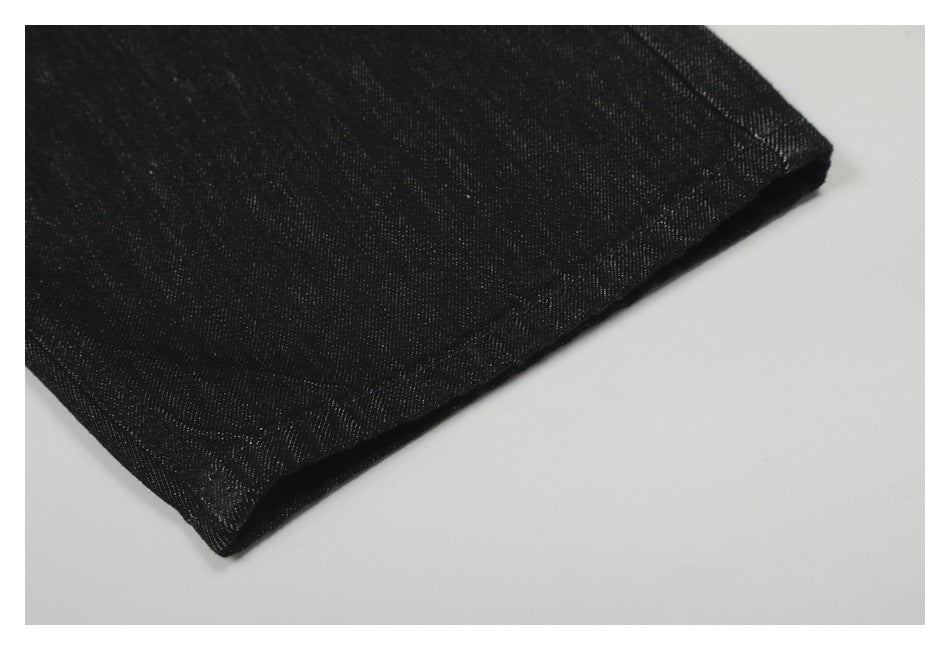 Close-up of the hem of black denim pants laid on a light surface.